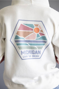 Close-up of the back of a white hoodie featuring a large hexagonal graphic with a retro sunset landscape and the text 'MICHIGAN' and 'LIVIN THE DREAM'.