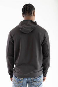 Back view of a model wearing a dark raven black long-sleeve hooded sweatshirt with the hood down, paired with light-wash blue jeans featuring white contrast stitching.