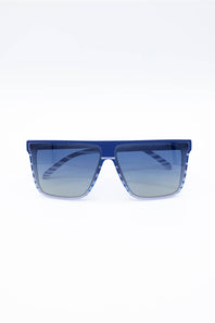 A pair of oversized square sunglasses with a translucent blue frame and gradient blue lenses, shown against a plain white background.
