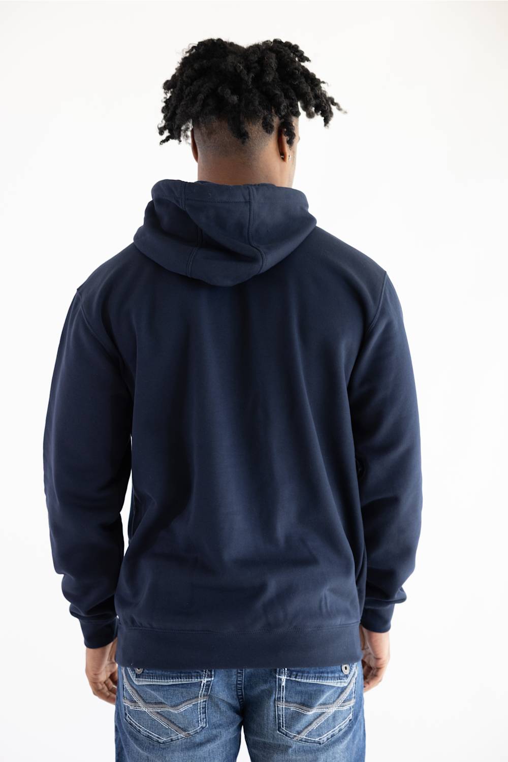 A man viewed from behind wearing a navy blue pullover hoodie and blue jeans against a plain white background.