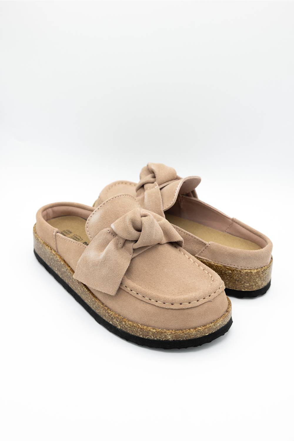 A single slip-on mule shoe in blush suede with a matching fabric bow on the vamp and a cork-textured midsole, shown against a plain white background.