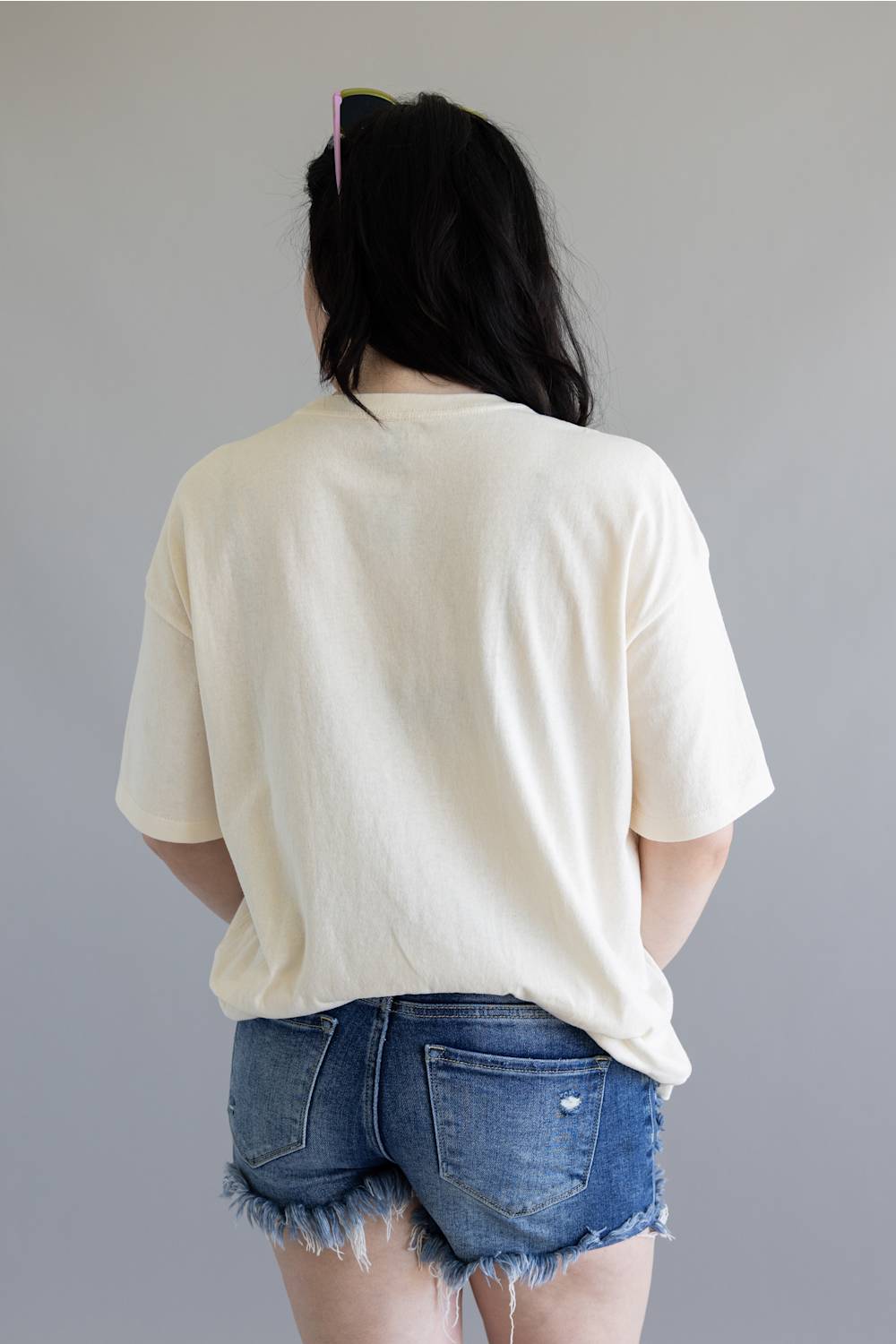 Person wearing a white t-shirt and denim shorts against a plain background