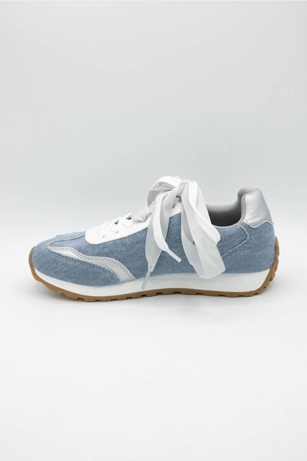 A light blue suede and canvas sneaker with oversized white laces, a white midsole, and a brown gum outsole, shown from a side profile on a light gray background.