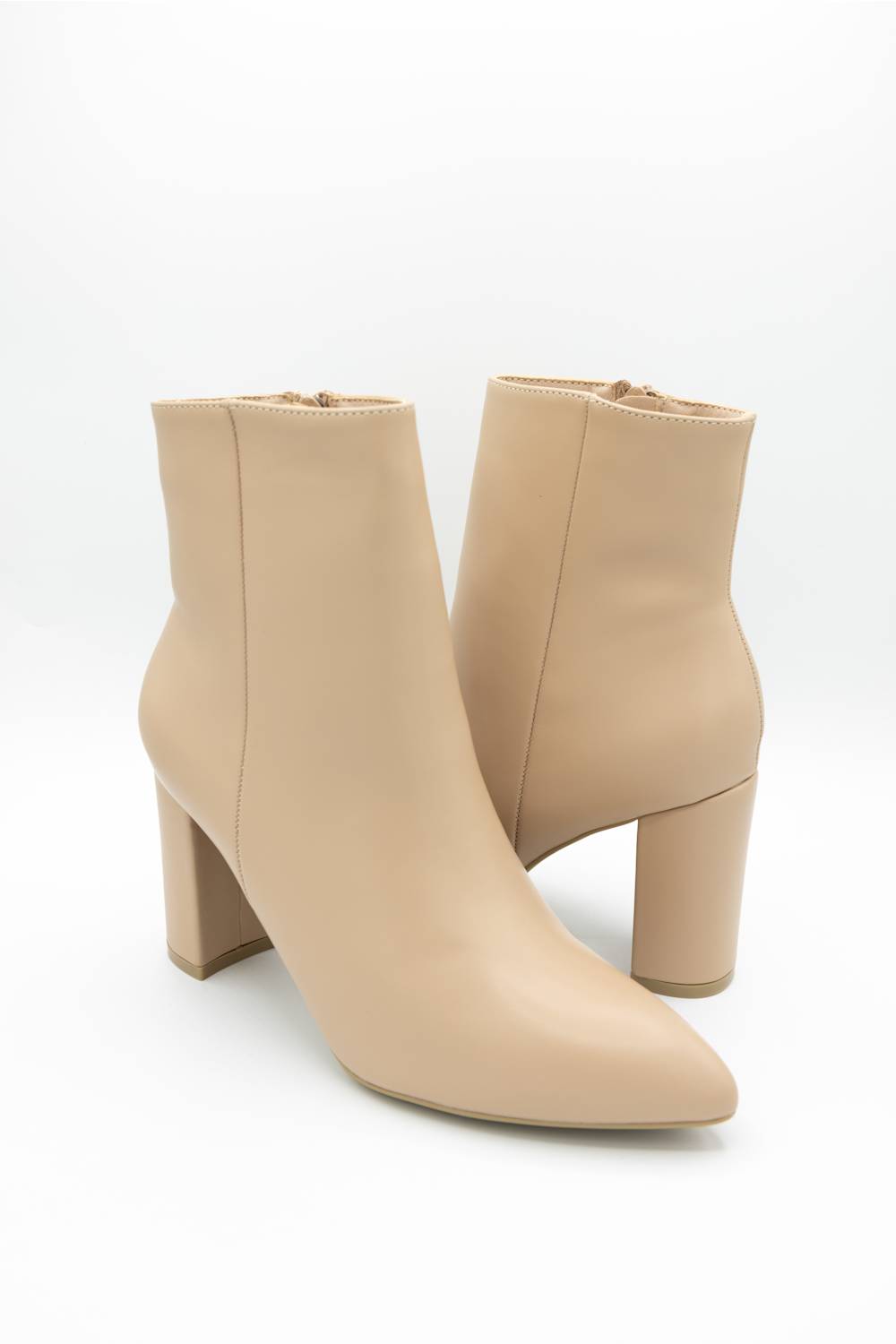 A pair of beige leather ankle boots with pointed toes and chunky block heels, photographed on a clean white studio background.