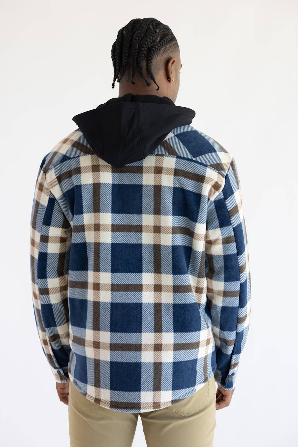 A man viewed from behind wearing a blue, brown, and beige plaid hooded flannel shirt over a black hoodie, paired with khaki pants, against a plain white background.