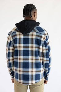 A man viewed from behind wearing a blue, brown, and beige plaid hooded flannel shirt over a black hoodie, paired with khaki pants, against a plain white background.