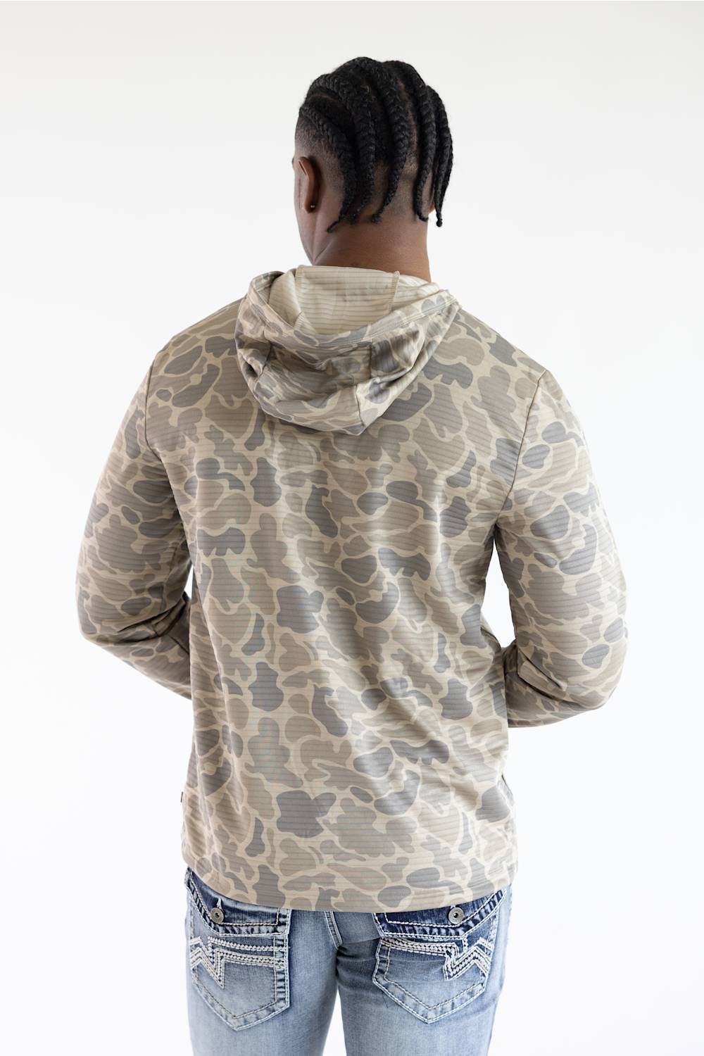 A person shown from the back wearing a beige and gray camouflage-patterned hoodie and light blue jeans against a plain white background.