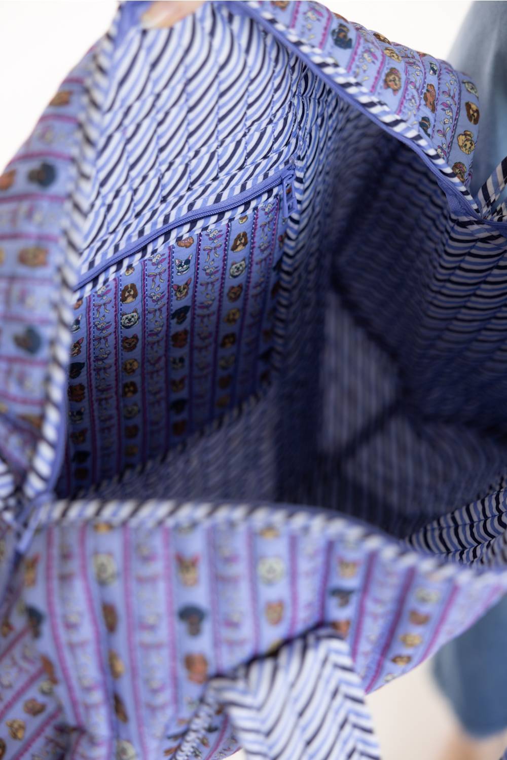 Close-up of a fabric bag or pouch interior with a striped and patterned design in purple, blue, white, and small multicolor motifs.