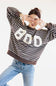 A woman posing in a brown and white horizontally striped sweatshirt with a large white BOO graphic on the front, paired with light blue jeans, against a plain white background.