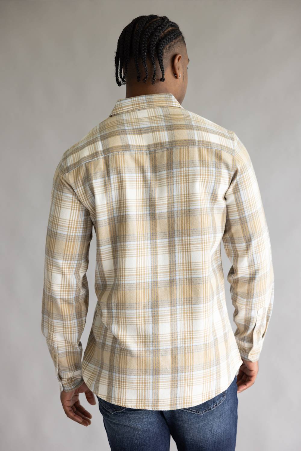 Back view of a model wearing the Split Men's long-sleeve flannel shirt in a beige, white, and light blue plaid pattern, featuring a straight back yoke and rounded hem line against a grey studio background.