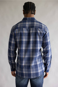 Back view of a model wearing the Split Men's long-sleeve flannel shirt in a navy blue, khaki, and white plaid pattern, featuring a straight back yoke and rounded hemline against a grey studio background.