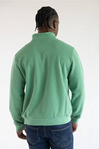 A photo from the back of a man wearing the The North Face Evolution Simple Dome ¼ Zip Neck for Men in Dimmed Algae Green with a white The North Face Logo on the upper left chest.