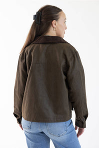 A woman shown from the back wearing a dark brown jacket and light blue jeans against a plain white studio background.