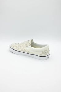 A single slip-on platform sneaker by Vans, featuring a cream and white checkerboard pattern with raised studs on the toe box, a thick white platform sole, and a thin black stripe along the midsole.