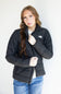 A woman wearing a black puffer jacket by The North Face, styled with a white t-shirt and blue jeans, standing against a plain white background.