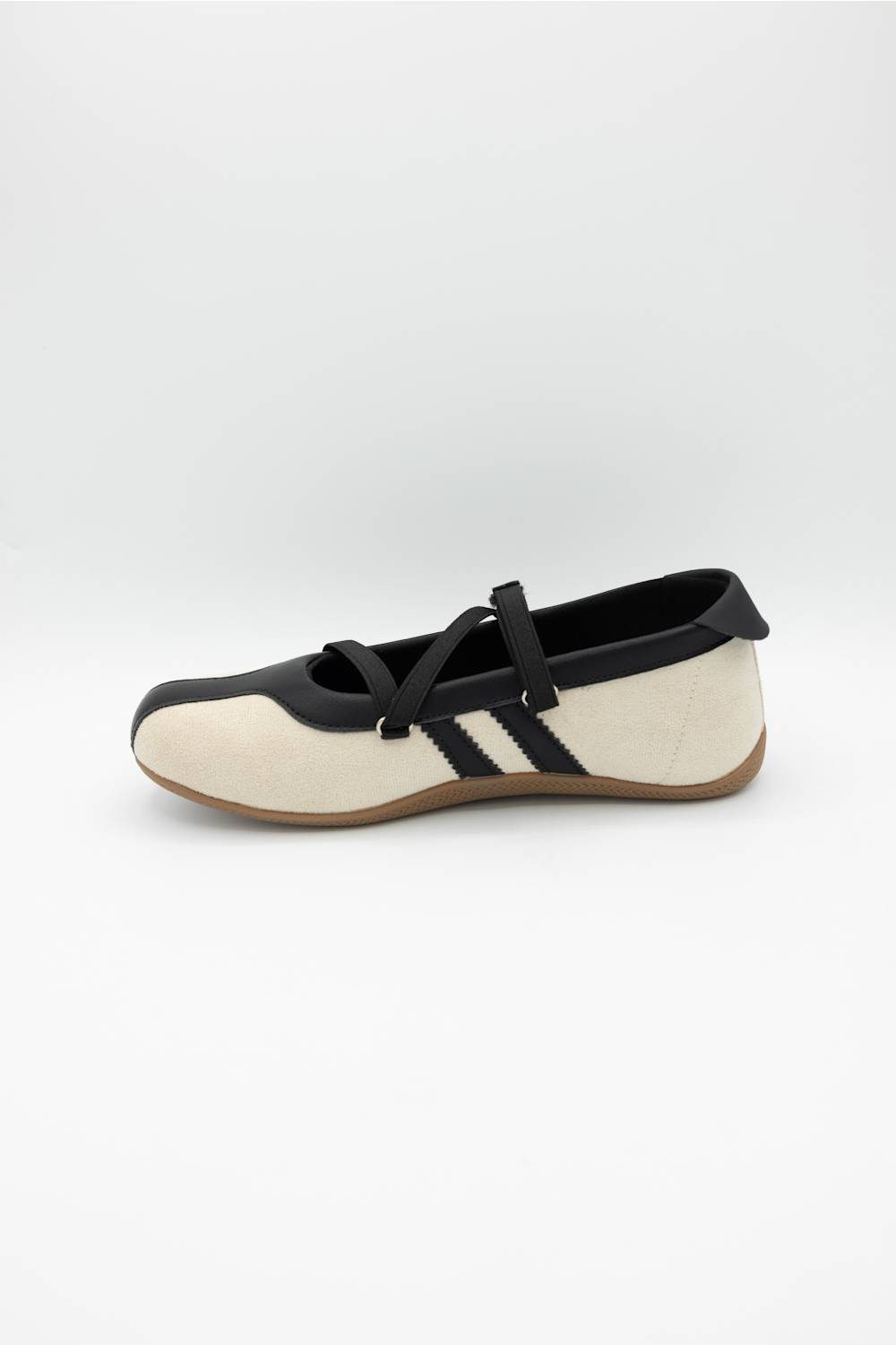 A single women's Mary Jane flat shoe in off-white and black, featuring a black strap with a silver buckle and three black stripes on the side, set against a plain light gray background.