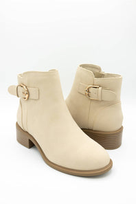 A pair of beige ankle boots with a low block heel and a decorative strap with a gold buckle on the outer side, shown against a plain white background.