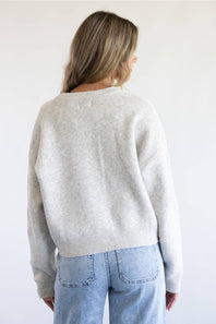 A woman modeling a light gray knit cardigan plain white background.