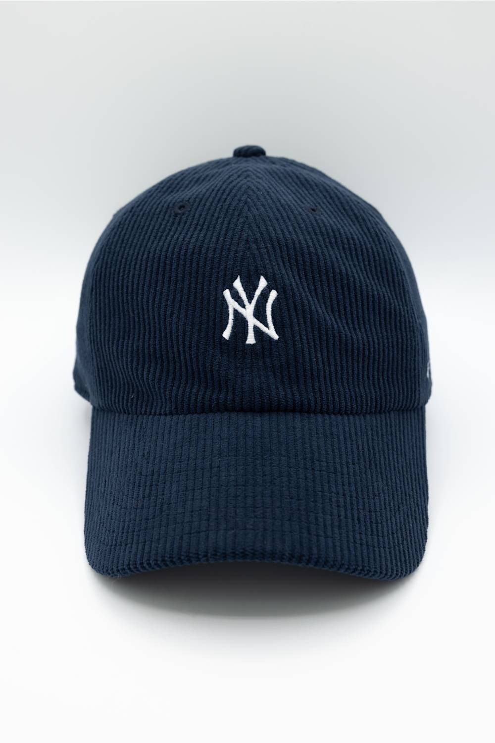 A navy blue corduroy baseball cap featuring the white embroidered New York Yankees logo on the front, set against a clean white background.
