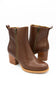 A pair of brown leather ankle boots with side zippers, block heels, and pull tabs, shown on a plain white background.