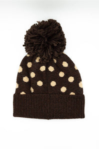 C.C. Polka Dot Pom Beanie for Women in Brown. Flat lay product photo of the back of the knit hat, showing the brown main color, cream polka dots, dark brown fuzzy pom-pom, and ribbed cuffed hem.