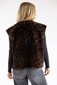 A woman shown from the back wearing a brown leopard-print faux fur vest over a black long-sleeve top and gray jeans, against a plain white background.
