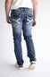 Rear view of a person wearing blue denim jeans with distinctive white contrast stitching and decorative stitching on the back pockets, paired with a white t-shirt and white sneakers.