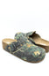 A pair of slip-on clogs with a green and brown woodland camouflage pattern, featuring a cork wedge heel and a black buckle strap across the top, shown on a white background.