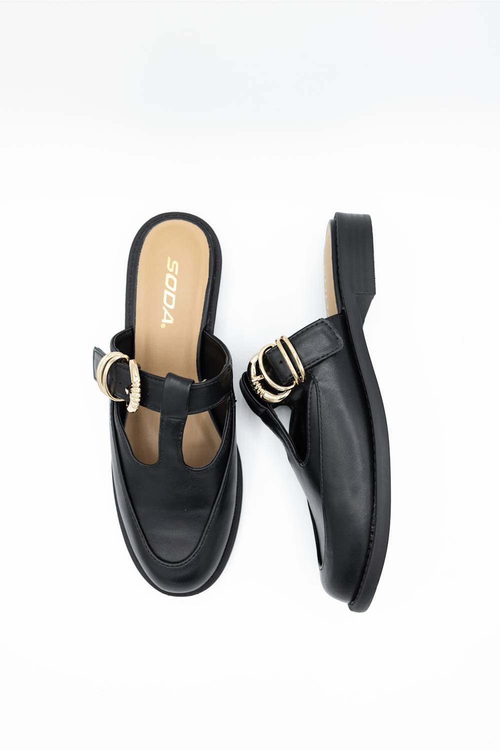 A pair of black leather T-strap mule sandals with gold-tone metal hardware, shown from top and side views on a white background. The insole features the brand name 'SODA' in gold lettering.