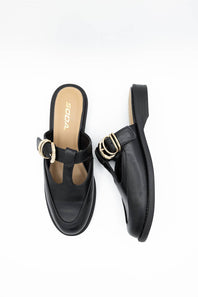 A pair of black leather T-strap mule sandals with gold-tone metal hardware, shown from top and side views on a white background. The insole features the brand name 'SODA' in gold lettering.