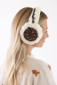 A woman shown from the side wearing fluffy white earmuffs with a leopard print inner panel, against a clean white background.