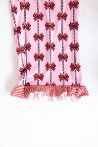 Pink fabric accessory with a repeating red bow and striped vertical motif, finished with a red-and-white striped ruffled hem, shown against a plain white background.