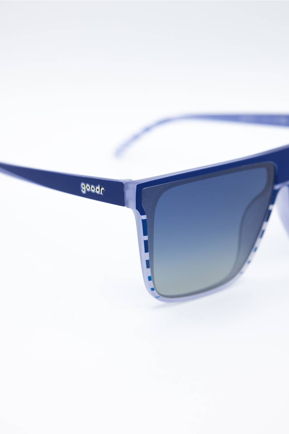 Close-up of blue-framed sunglasses with gradient blue lenses and a visible 'goodr' logo on the temple, photographed on a clean white background.