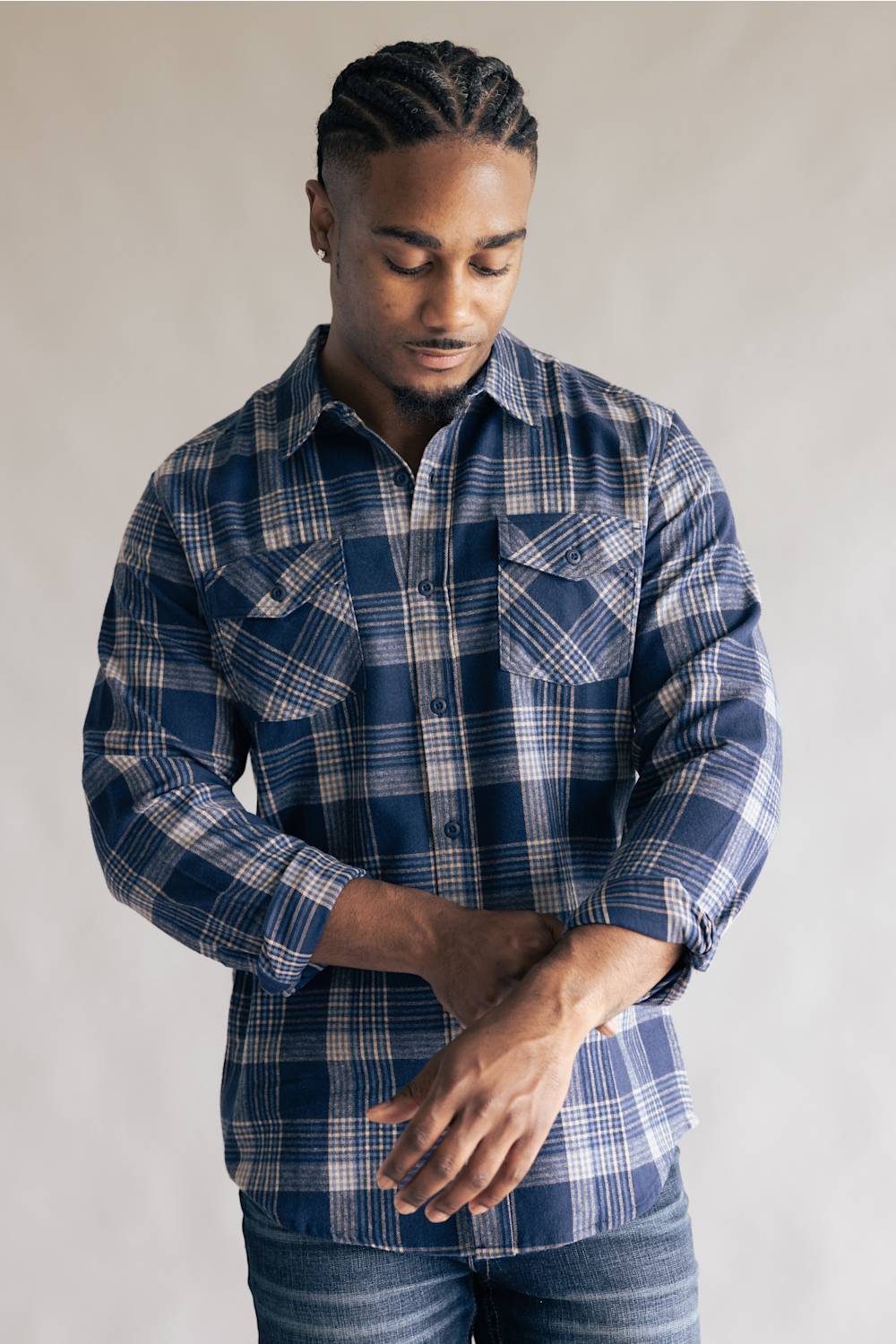 Model wearing the Split Men's long-sleeve flannel shirt in a navy blue, khaki, and white plaid pattern, featuring two chest flap pockets with button closures and buttoned cuffs against a grey studio background.