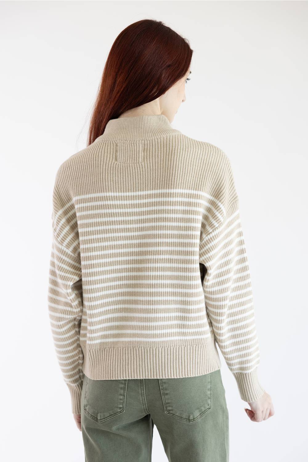 A woman shown from the back wearing a beige and off-white striped knit sweater and olive green pants against a plain white background.