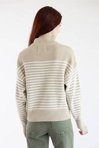 A woman shown from the back wearing a beige and off-white striped knit sweater and olive green pants against a plain white background.