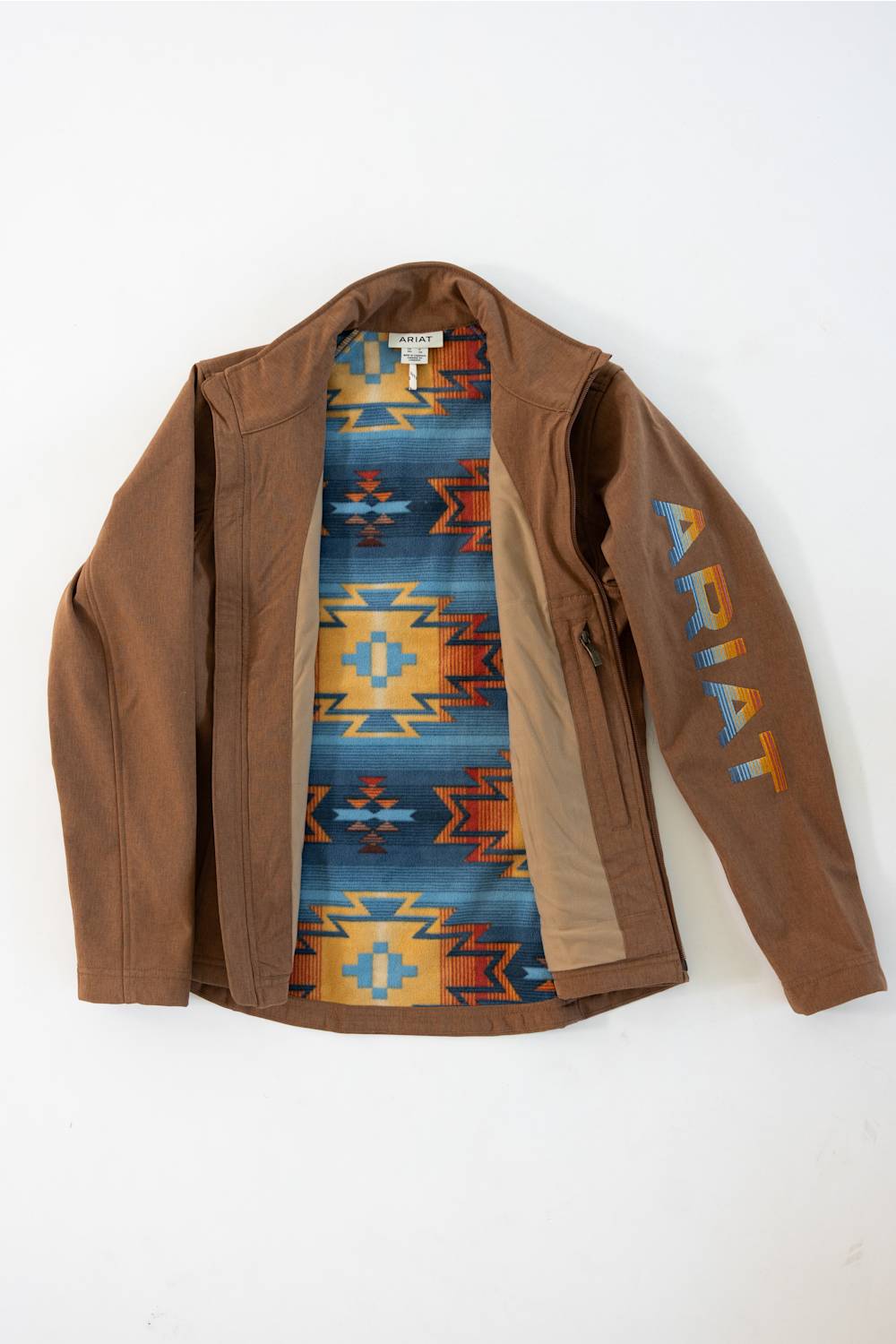 A brown leather jacket with a colorful Southwestern patterned lining and ARIAT printed vertically on the sleeve, laid flat against a white background.