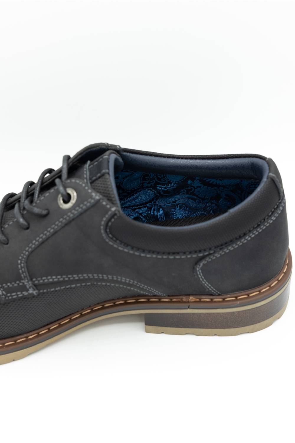 A close-up side view of a dark gray suede lace-up shoe with a brown welt and a blue patterned lining, set against a plain white background.