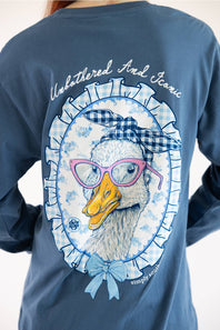 A person wearing a slate blue long-sleeve shirt, showing the back graphic. The graphic features a cute duck illustration wearing pink glasses and a blue-and-white gingham bow headband, framed by a blue-and-white gingham ruffled border with the text 'Unbothered And Iconic' above it.