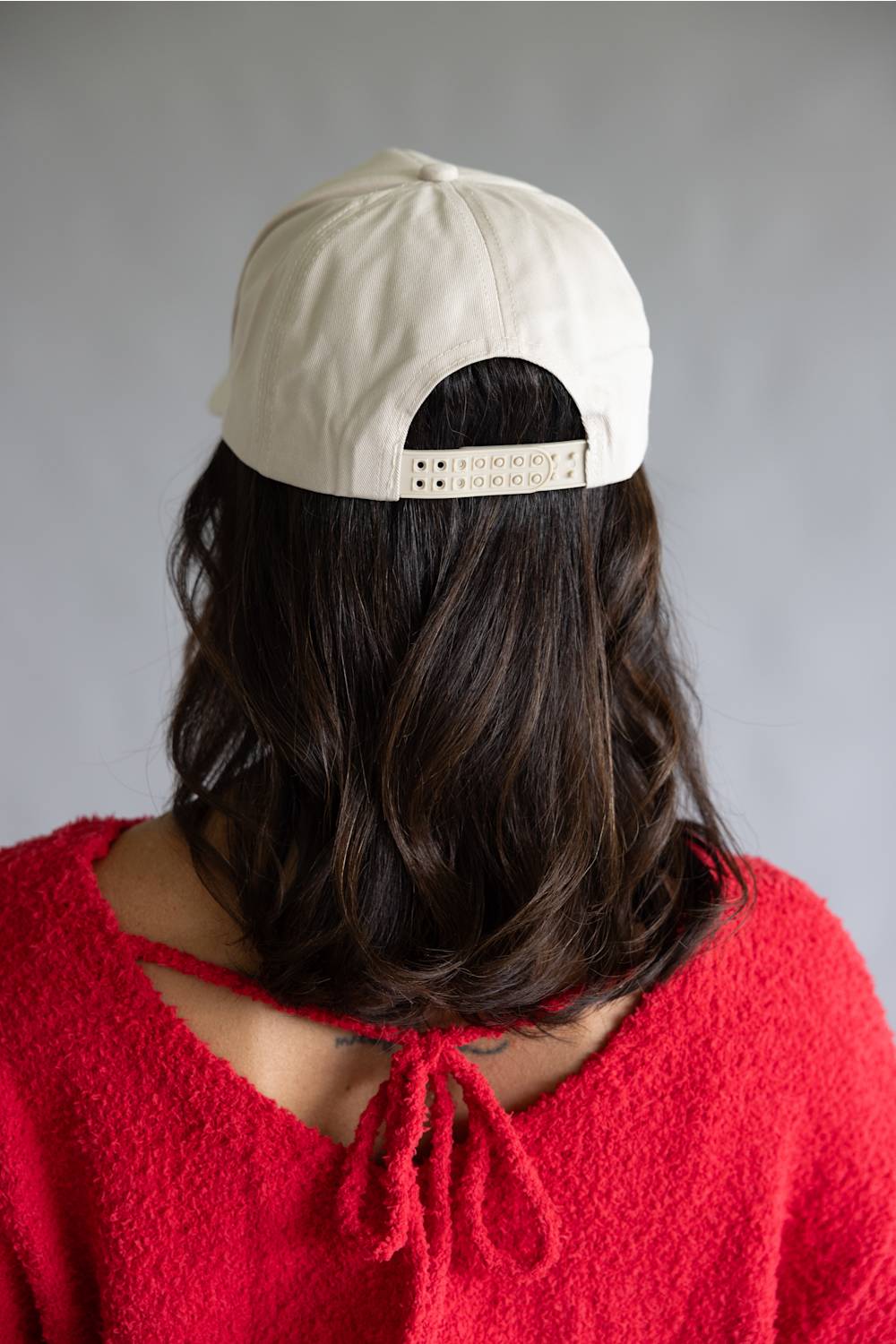 Woman wearing a beige cap with a gray background