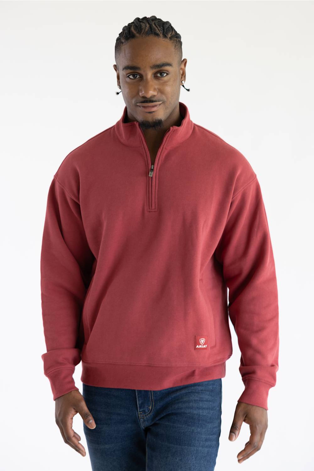 A man wearing a red quarter zip sweatshirt with front pockets and a small red Ariat patch on the left front pocket.