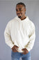 A man wearing an off-white pullover hoodie with drawstrings and a front kangaroo pocket, paired with blue jeans, standing against a solid gray studio background.