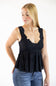 A woman wearing a black sleeveless lace-trimmed ruffled top and blue jeans, standing against a plain white studio background.