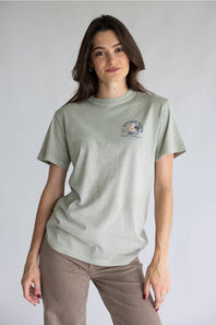 A light beige crewneck t-shirt with a colorful floral graphic on the back, featuring the text 'LET KINDNESS BLOOM' and 'simply southern.' COLLECTIONS.