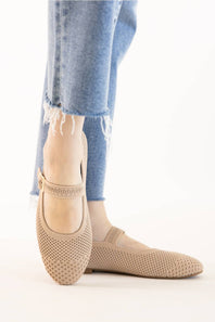 Side profile and front view of a model wearing beige knit mesh Mary Jane flats paired with light blue frayed denim jeans.