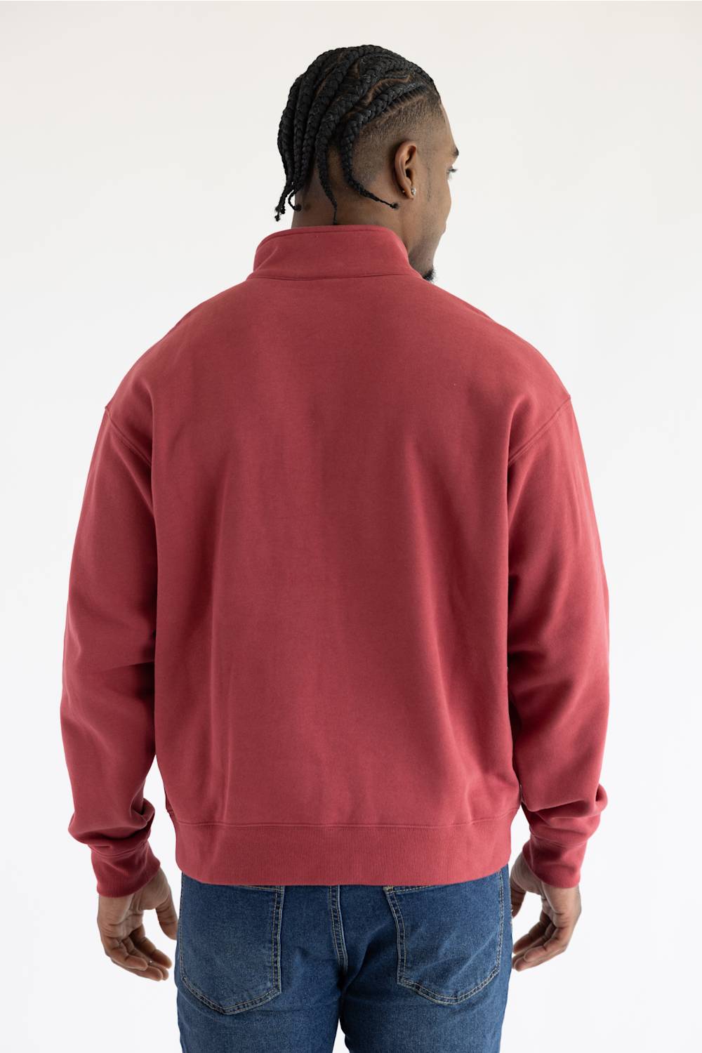 A man viewed from the back wearing a red quarter zip sweatshirt with front pockets and a small red Ariat patch on the left front pocket.