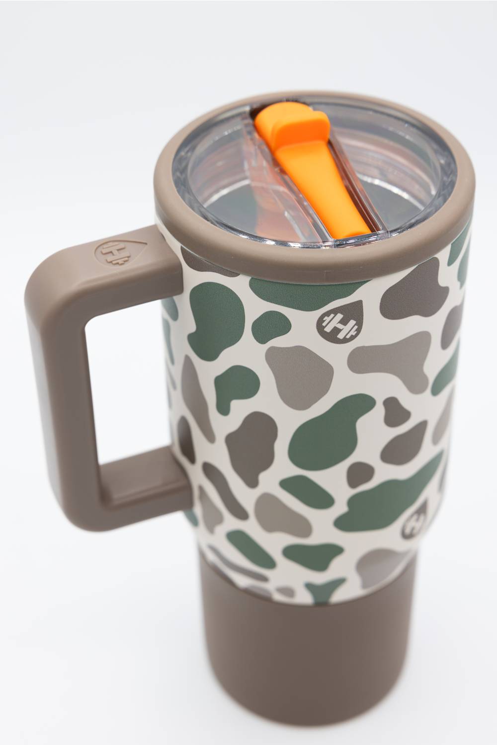 A travel tumbler with a handle, featuring a green and gray camouflage pattern on a white background, with a brown lid and handle, and an orange straw visible inside.