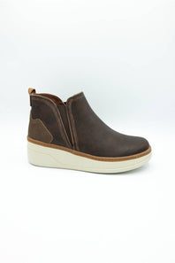 A dark brown suede ankle boot with a wedge heel and a thick off-white sole, shown from a side profile on a white background.