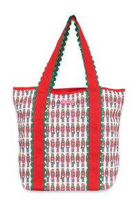 A tote bag featuring a white base printed with a repeating pattern of nutcracker soldiers, accented by bold red side panels and handles with green scalloped edges.