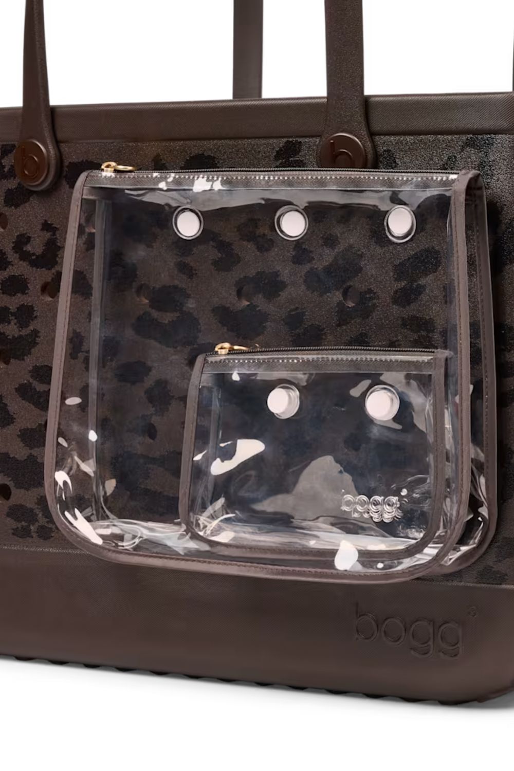 A close-up of a brown leather tote bag with a dark brown leopard print pattern and a clear plastic front pouch pocket with metal grommets. The brand name 'bogg' is embossed on the bottom right corner of the bag.